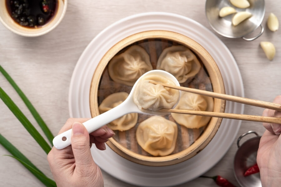 Xiaolongbao soup dumplings in bamboo steamer, black vinegar and ginger, Shanghai regional Chinese dish for travelers